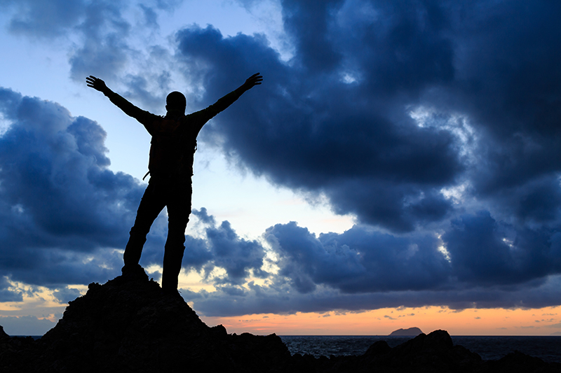 Success achievement silhouette hiking accomplishment business concept with man celebrating with arms up raised outstretched faith worship outdoors